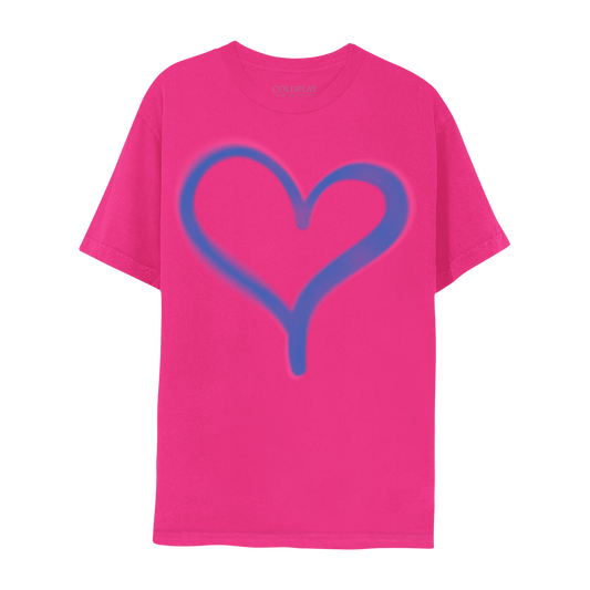 Front: A bright blue heart printed on the front of a bright pink tee in spray paint style with some areas looking a bit blurred. The left arch of the heart is wider than the right, and the tail of the heart is long. The heart sits in the center of the chest.