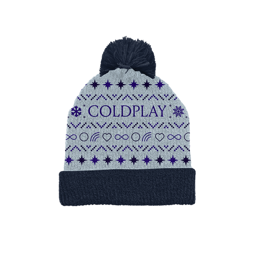 Festive light grey winter beanie, with a fluffy navy blue pom-pom. The word COLDPLAY is prominently displayed in purple letters on the front, surrounded by stars&snowflakes. With infinity symbols, heart outlines,&rainbows in between, all in dark blues&purples. The purple stars form symmetrical rows that repeat throughout. The hat is knitted, and looks very cozy. Its foldOver brim is navy blue, matching the color of the pom-pom, that highlights the fun spirit of the festive season